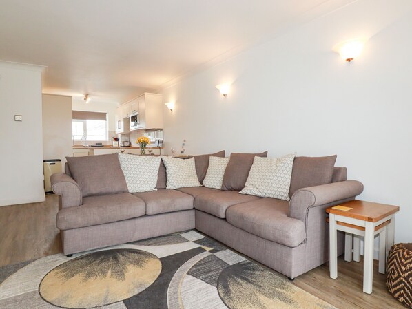 A modern living room with a sectional sofa, a small wooden table, and a patterned rug.