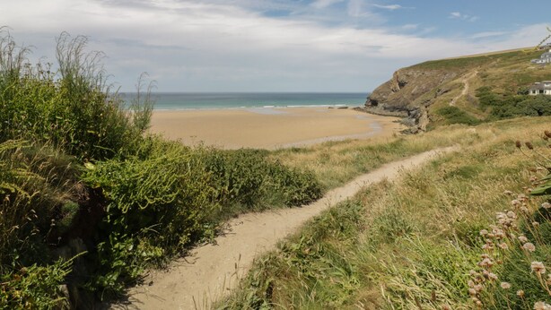 A coastal path leading to a sandy beach with a clear view of the ocean and a rocky cliff. - 7 Europa Court (Newquay)