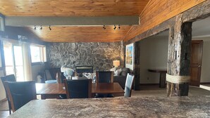 A dining area with a stone wall, wooden ceiling, and a granite countertop.