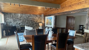 A dining area with a stone wall, wooden ceiling, and a painting on the wall.