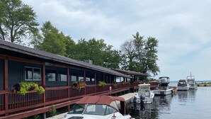A docked boat in front of a building with a wooden deck and potted plants.