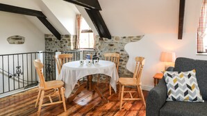 Un comedor acogedor con una mesa redonda, sillas de madera y un fondo de pared de piedra.