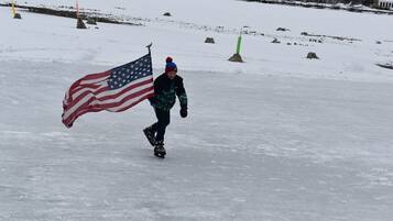 Une personne patine sur une surface enneigée, brandissant un drapeau américain.