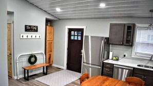 Una cocina moderna con refrigerador integrado, armarios de madera y un área de comedor con banco y mesa.