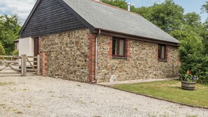 Un bâtiment en pierre avec un toit en pente, une porte en bois et une allée gravillonnée.