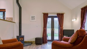 Un salon chaleureux avec une cheminée, un téléviseur et des fauteuils confortables.