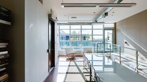 A modern hotel lobby with a glass staircase, a seating area, and a view of the outdoors.