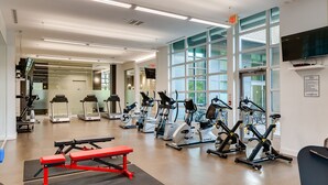 A gym with treadmills, elliptical machines, and a red bench.