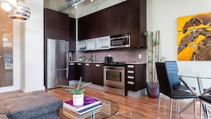A modern kitchen with dark cabinetry, stainless steel appliances, and a tiled backsplash.