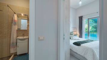 Una camera da letto con un letto grande, un bagno con doccia e vista sull'esterno.
