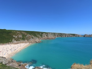 A beach with clear turquoise waters, sandy shore, and rocky cliffs.