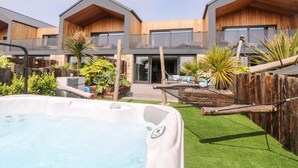 A modern outdoor pool area with a hot tub, surrounded by wooden cabins with balconies.