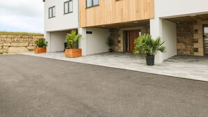 A modern two-story house with a stone wall, wooden facade, and potted plants.