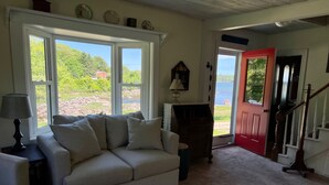 A living room with a beige sofa, a lamp, and a view of a lake through large windows.