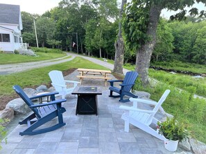 An outdoor patio with Adirondack chairs, a picnic table, and a fire pit.