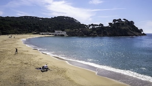 Una playa con arena, algunas personas y un edificio en una colina.