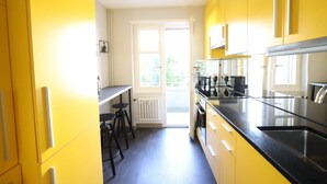 Een keuken met gele kastjes, een zwart aanrecht en een raam met uitzicht op groen.