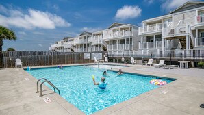 A swimming pool area with a wooden fence, lounge chairs, and a lifeguard stand. - "Waters Edge 427-B" - Oceanfront Condo w/ Community Pool, 2 Bedrooms / 2 Bathrooms (Holden Beach)