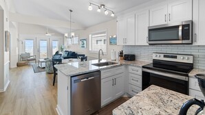 A modern kitchen with white cabinets, a built-in microwave, and a dishwasher. - "Waters Edge 427-B" - Oceanfront Condo w/ Community Pool, 2 Bedrooms / 2 Bathrooms (Holden Beach)