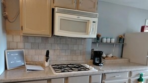 A kitchen with a gas stove, a microwave, cabinets, and a welcome sign. - Apartment Attached to a 1900 historic Farm house (Old Mill Creek)