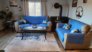 Ein gemütliches Wohnzimmer mit blauer Sofagarnitur, einem Couchtisch und einem Kamin.