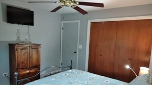 A bedroom with a bed, wooden wardrobe, ceiling fan, and a door. - Apartment Attached to a 1900 historic Farm house (Old Mill Creek)