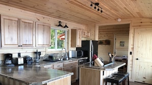 A modern kitchen with wooden cabinets, granite countertops, and stainless steel appliances. - Cozy Lakefront Cabin on Big Lake, Alaska (Big Lake)
