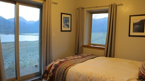 Una camera da letto con una grande finestra che offre vista su un lago e montagne.