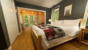 Ein Schlafzimmer mit einem hölzernen Bett, einer Steppdecke, einem Nachttisch mit Lampe und einem Fenster mit Bärenbild.
