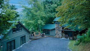 Eine Lodge mit Steineingang, überdachter Terrasse und Schotterzufahrt.