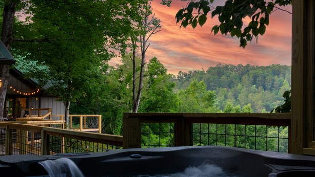 Ein Whirlpool mit Wasserfall, umgeben von einer Holterrasse und Blick auf einen bewaldeten Bereich.