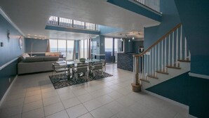 Un vaste espace de vie comprenant une table à manger, un canapé et un escalier menant à un niveau supérieur.