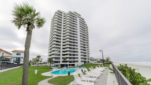 Un hôtel de grande hauteur doté d’un espace piscine, comprenant des chaises longues et un palmier.