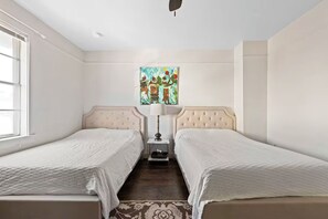 A twin room with two beds, a nightstand, a lamp, and a painting on the wall.