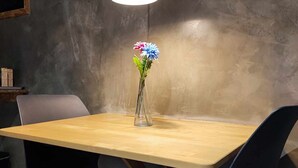 A dining table with a vase of flowers, two chairs, and a hanging light fixture. - Ruby Charm Houses 12 116354/AL (Porto)