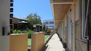 A corridor with a wooden ceiling, a small garden area with potted plants, and a building with a stone facade. - Ruby Charm Houses 12 116354/AL (Porto)