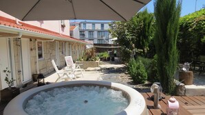 A hot tub surrounded by outdoor furniture, a wooden deck, and potted plants. - Ruby Charm Houses 12 116354/AL (Porto)