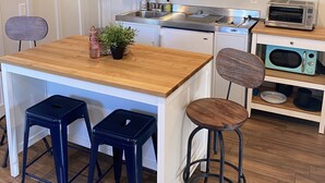A compact kitchen with a wooden countertop, two stools, a sink, a toaster, and a microwave. - Our Lucky Charm is a cottage on the waterway in Hatteras Village  (Hatteras)