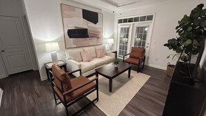 A living room with a sofa, two armchairs, a coffee table, a ceiling fan, and a large abstract painting. - Fabulous 3 Bedroom/ 2 Bath in Alpharetta (Alpharetta)