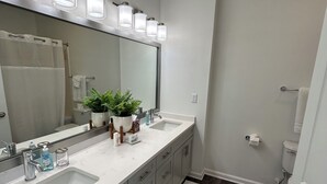A modern bathroom with a large mirror, two sinks, a shower, and a toilet. - Fabulous 3 Bedroom/ 2 Bath in Alpharetta (Alpharetta)
