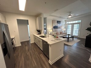 Una cocina moderna con una isla central, electrodomésticos integrados y un rincón de comedor con sofá y mesa de centro.