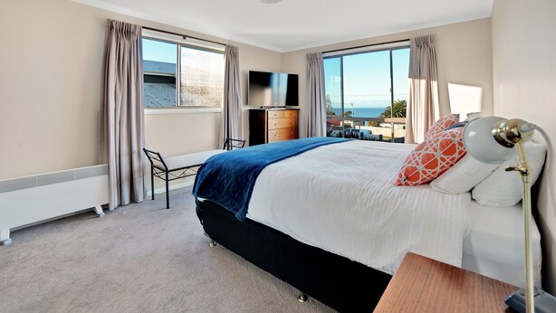 Una camera d'albergo con un letto, una scrivania, una TV e vista mare.