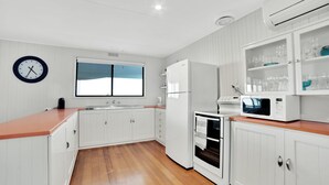 Una cucina moderna con mobili bianchi, un piano di lavoro in legno, forno integrato, microonde e una finestra con vista.