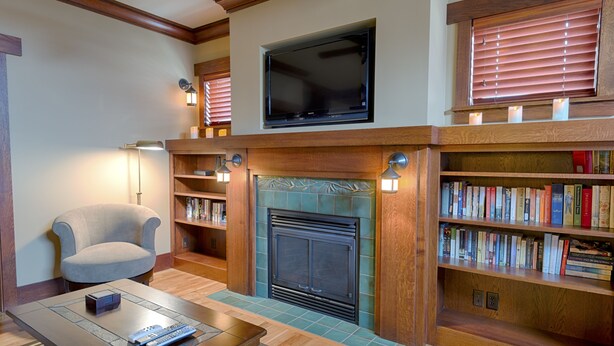 A living room with a fireplace, bookshelves, a television, and a comfortable armchair.