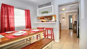 Un comedor con una mesa de madera, cortinas rojas y un cartel que indica un mercado.