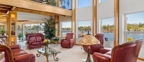 A spacious living area with leather sofas, a glass coffee table, and a view of a lake.