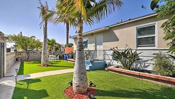 Un patio trasero residencial con césped, palmeras y una casa.