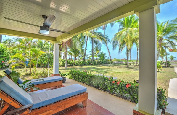 A covered outdoor area with wooden lounge chairs and a ceiling fan.