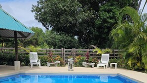 Una piscina con sillas reclinables blancas y esculturas de piedra decorativas.