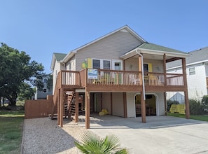 Stunning two-story home with a covered porch and wooden deck, featuring a gabled roof and front entrance.